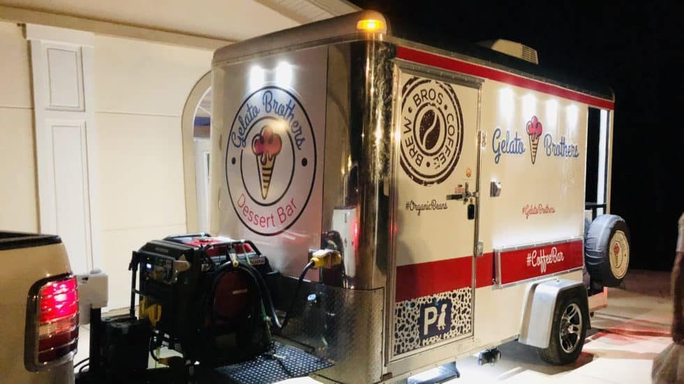 Vintage-style red and cream catering trailer with ice cream branding displayed at night with equipment visible.