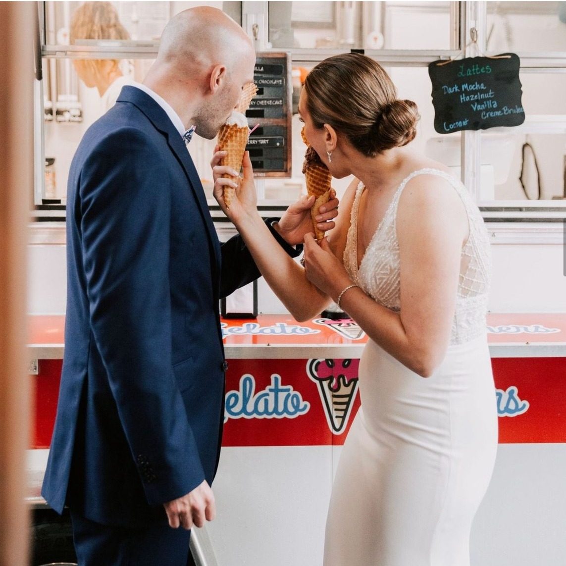 A couple in formal attire enjoying gelato together at a vintage ice cream cart.